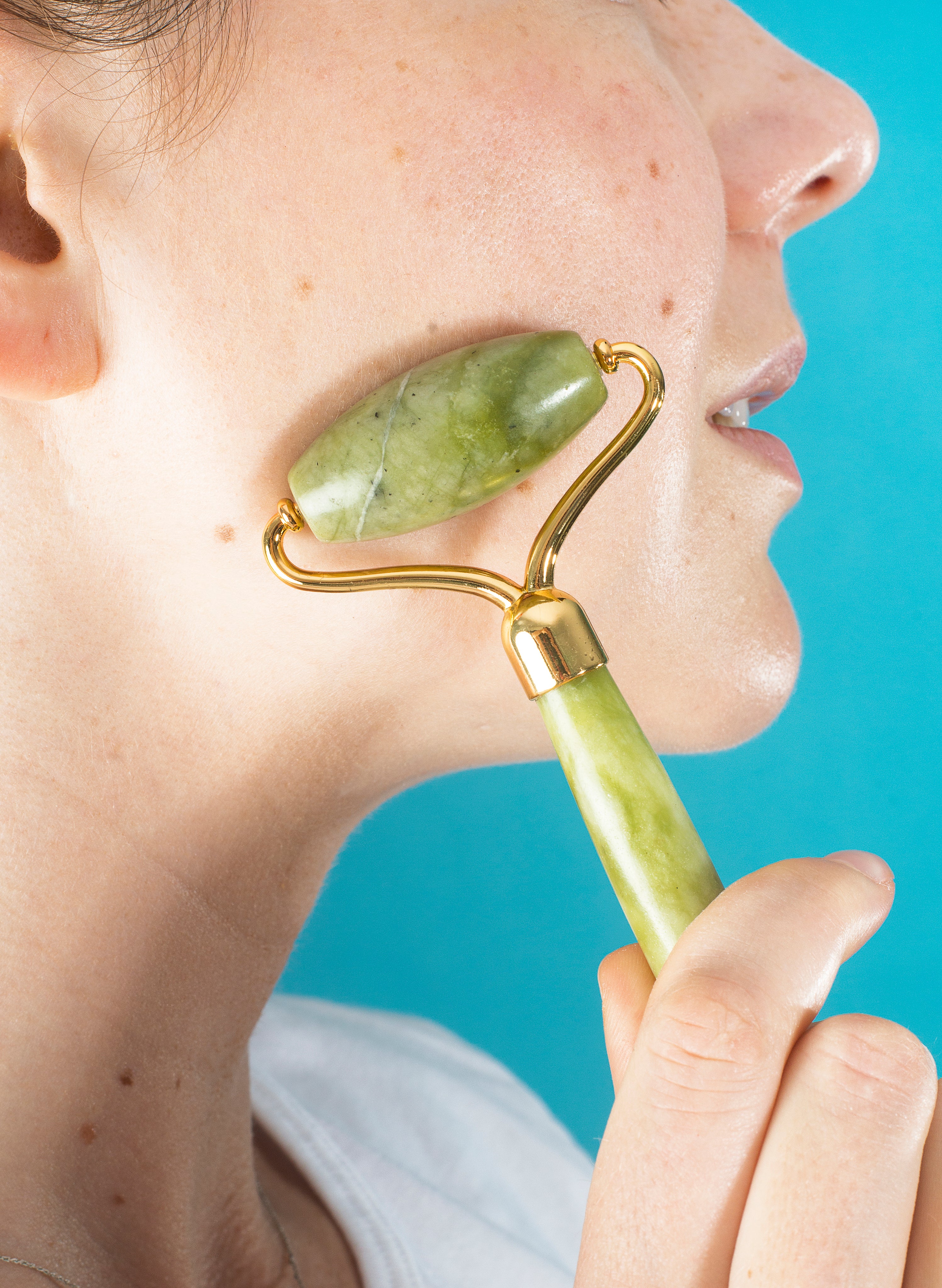 Woman using a jade roller on her cheek — natural face lifting products and buy handmade skincare online | natural skincare products online UK.